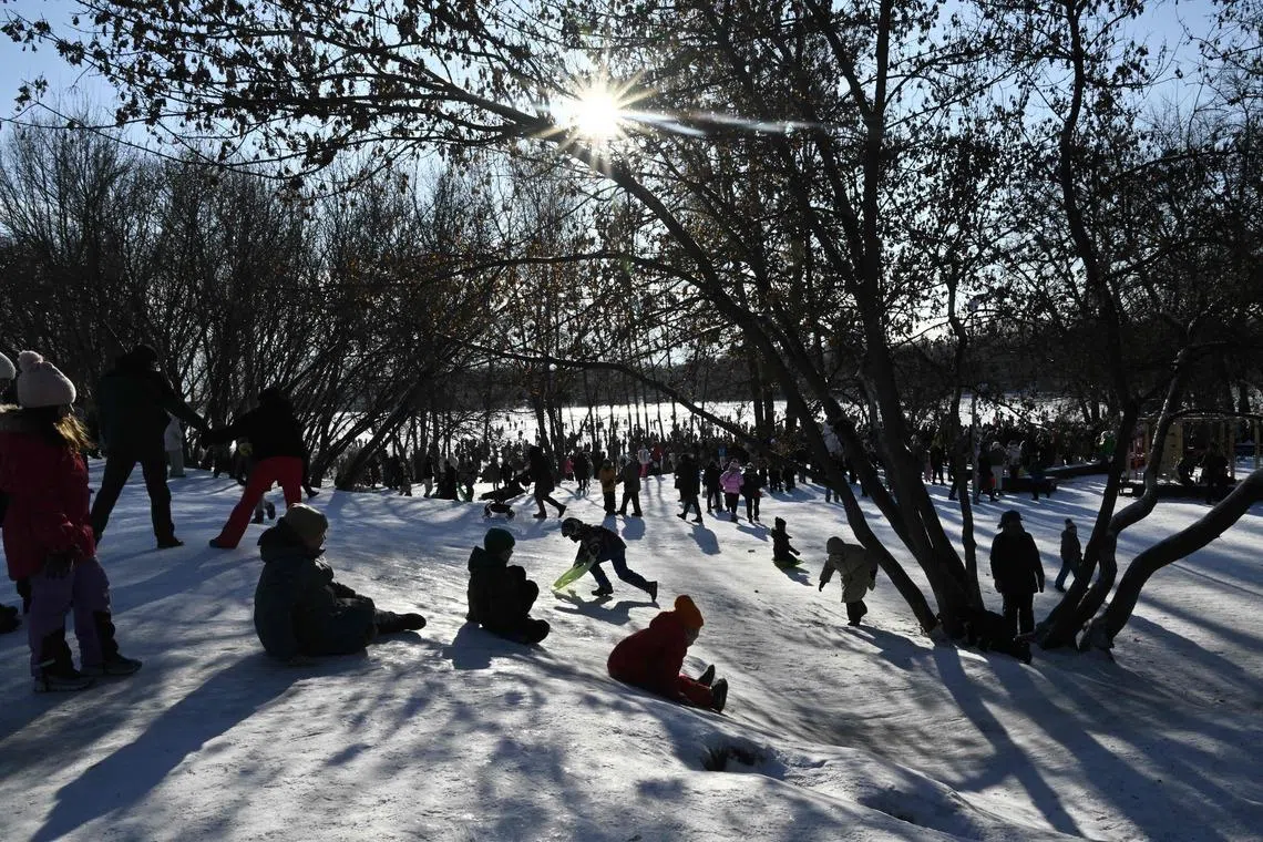 Children sliding down on the snowy bank of the frozen Dnipro River during an outdoor party in a residential neighbourhood of Kyiv, Ukraine on Jan 31, 2026, during mass power outages amid the Russian invasion of Ukraine. 