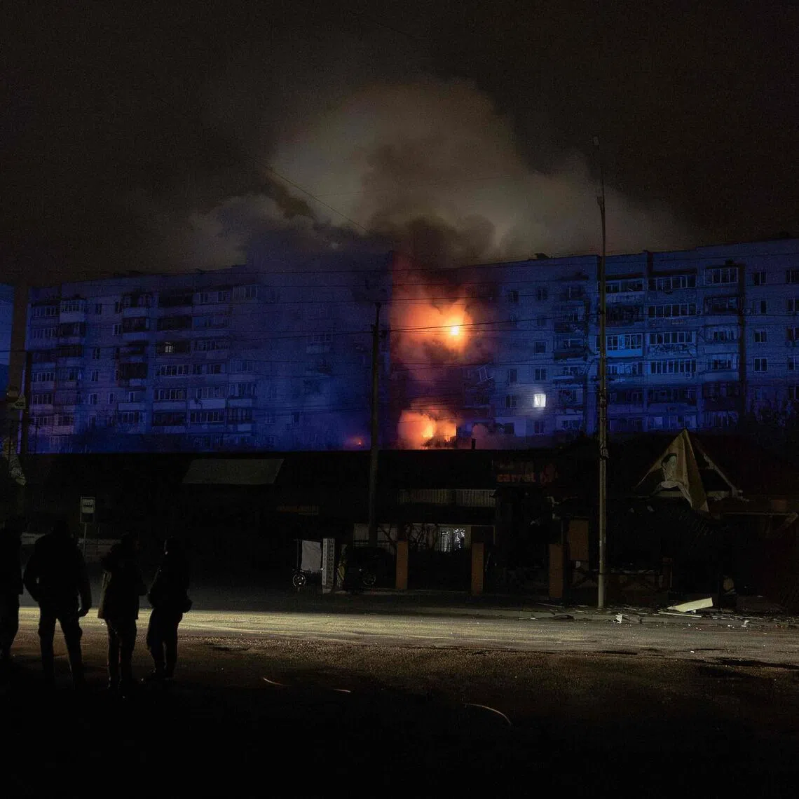 People look at a residential building on fire following a Russian drone attack on the city of Vyshhorod, in the Kyiv region early on Nov 30, 2025.