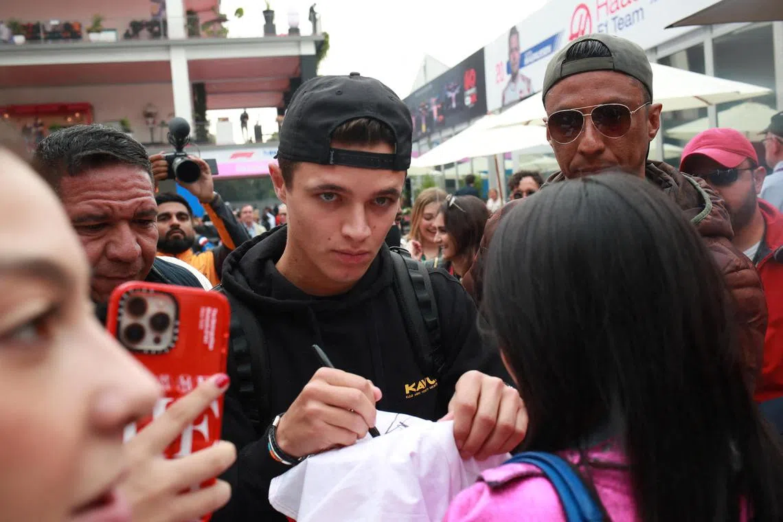 McLaren's Lando Norris signs autographs for fans ahead of practice at the Mexico Grand Prix.