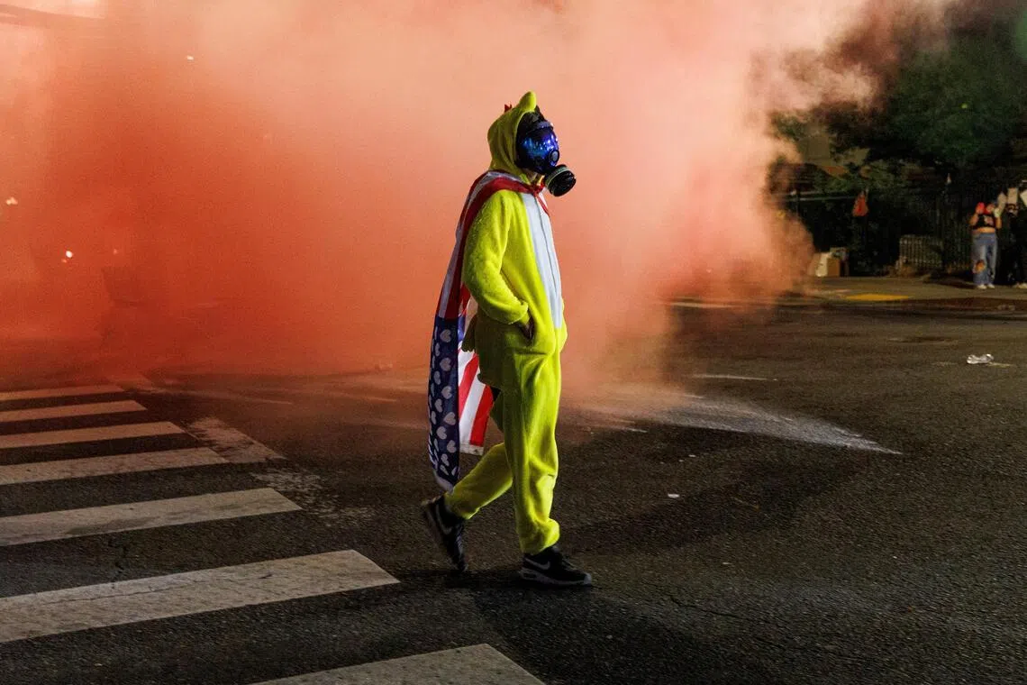 A protester walking amid tear gas and red smoke, during a protest against the Trump administration's immigration policies, outside an ICE detention facility in Portland, Oregon, on Sept 1.