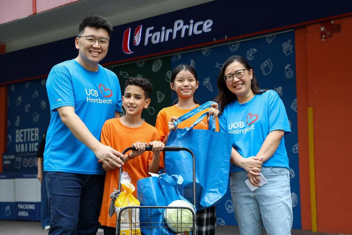 UOB Heartbeat volunteers Derrick Sin (left) and Jane Lai (right) with Aaron Kishen Arun Pandian Pillai, 11, and Najwa Chua Ai Xin, 12.
