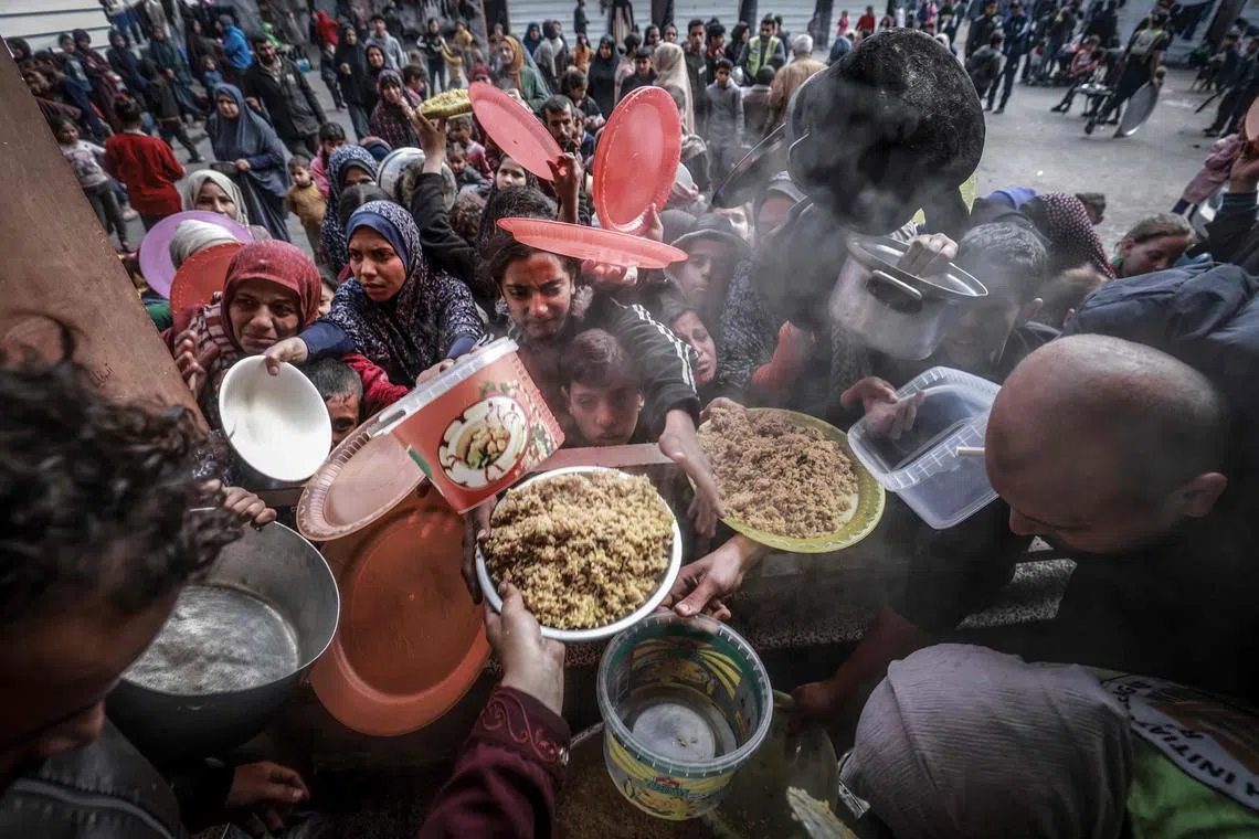 Displaced Palestinians gathering to receive food at a government school in Rafah in the southern Gaza Strip on February 19, 2024, amid the ongoing battles between Israel and the militant group Hamas. 