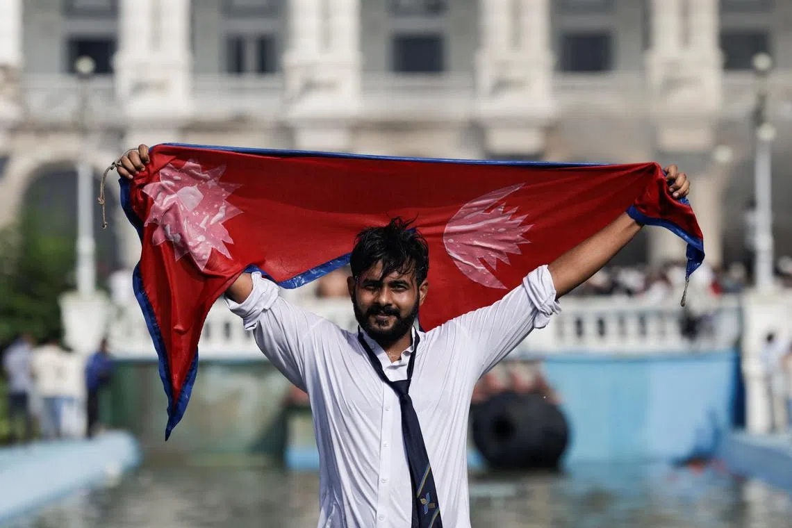 A demonstrator holding Nepal's flag celebrates at the Singha Durbar office complex, that houses the Prime Minister's office and other ministries, during a protest against Monday's killing of 19 people after anti-corruption protests that were triggered by a social media ban, which was later lifted, during a curfew in Kathmandu, Nepal, September 9, 2025. REUTERS/Navesh Chitrakar