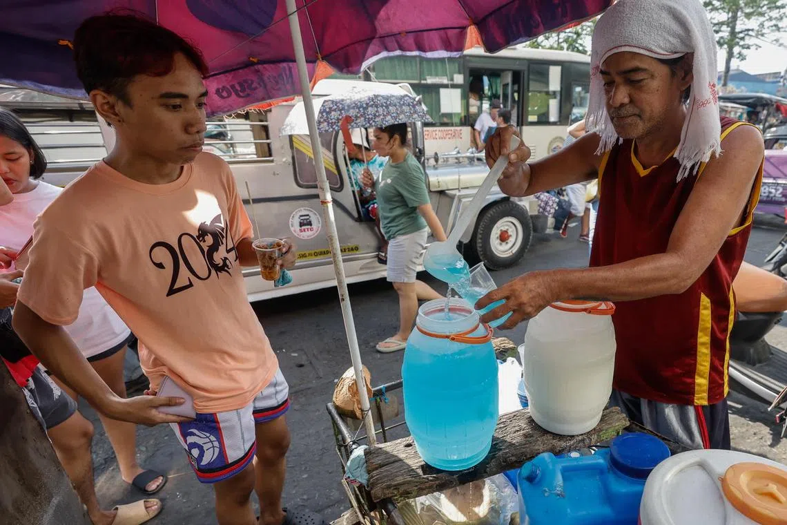 A refreshments vendor (right) attends to a customer in Pasig City, Metro Manila, on April 25. The Philippines' weather bureau has warned that the unusually hot weather was expected to last until mid-May. 