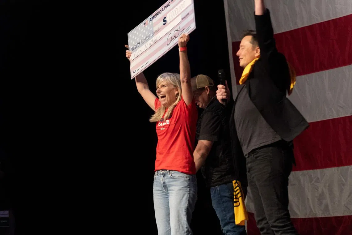 Billionaire Elon Musk (right) handed US$1 million cheques to two separate people over the weekend, including a woman in Pittsburg on Oct 20.