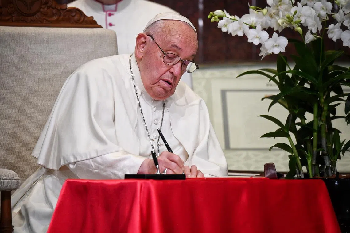 Pope Francis signing the visitor’s book at the welcome ceremony.