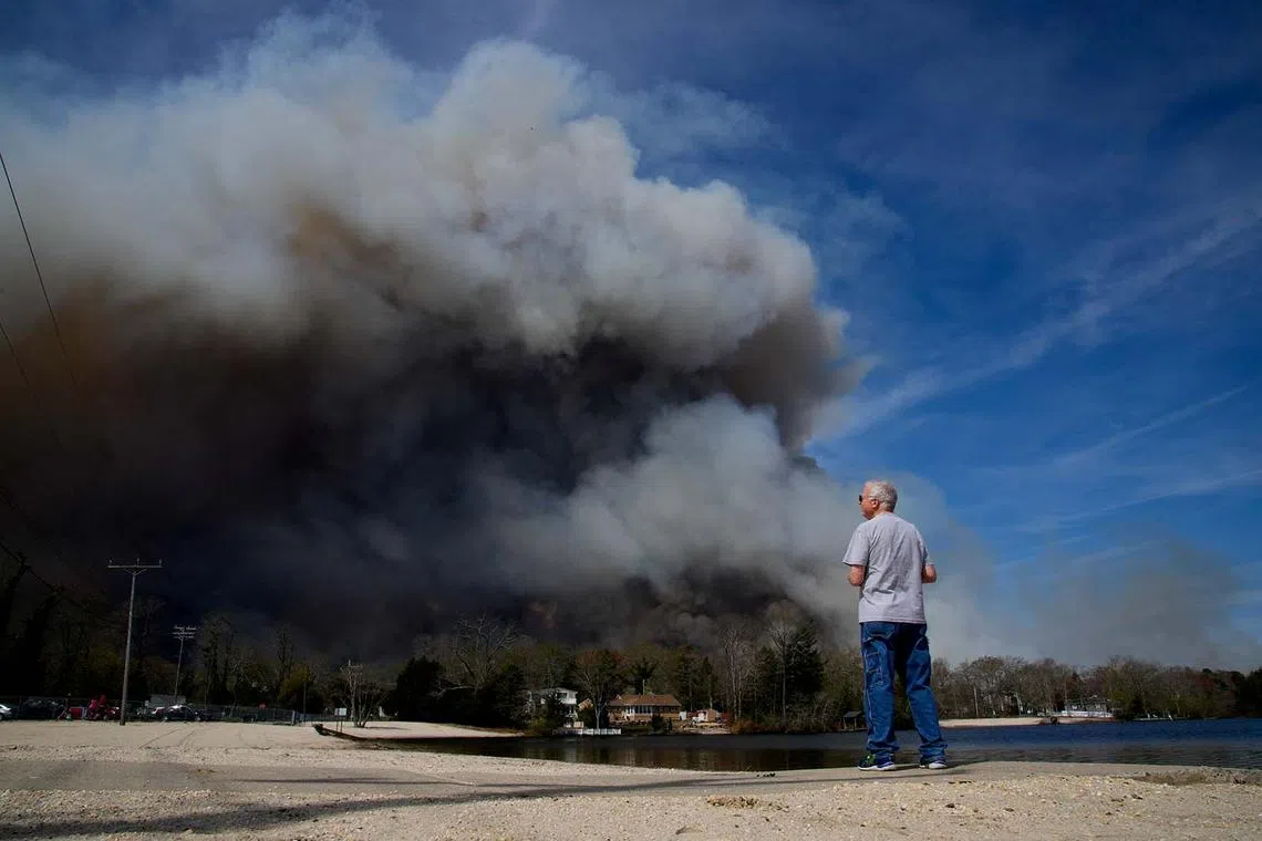 A man looking at smoke emerging from a wildfire in Lacey Township, in the Ocean County region of New Jersey, US, April 23, 2025. 