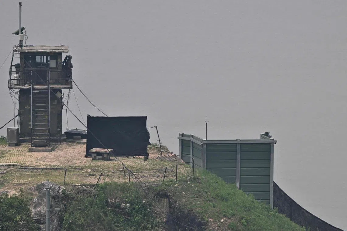 A South Korean soldier stands guard near a military facility (R, green box) where loudspeakers dismantled in 2018 used to be, near the demilitarized zone separating the two Koreas in Paju on June 11, 2024. South Korean troops fired warning shots after North Korean soldiers briefly crossed the border this week, Seoul's military said on June 11, with tensions high over Pyongyang's trash-carrying balloons and the South's retaliatory loudspeaker campaign. (Photo by ANTHONY WALLACE / AFP)
