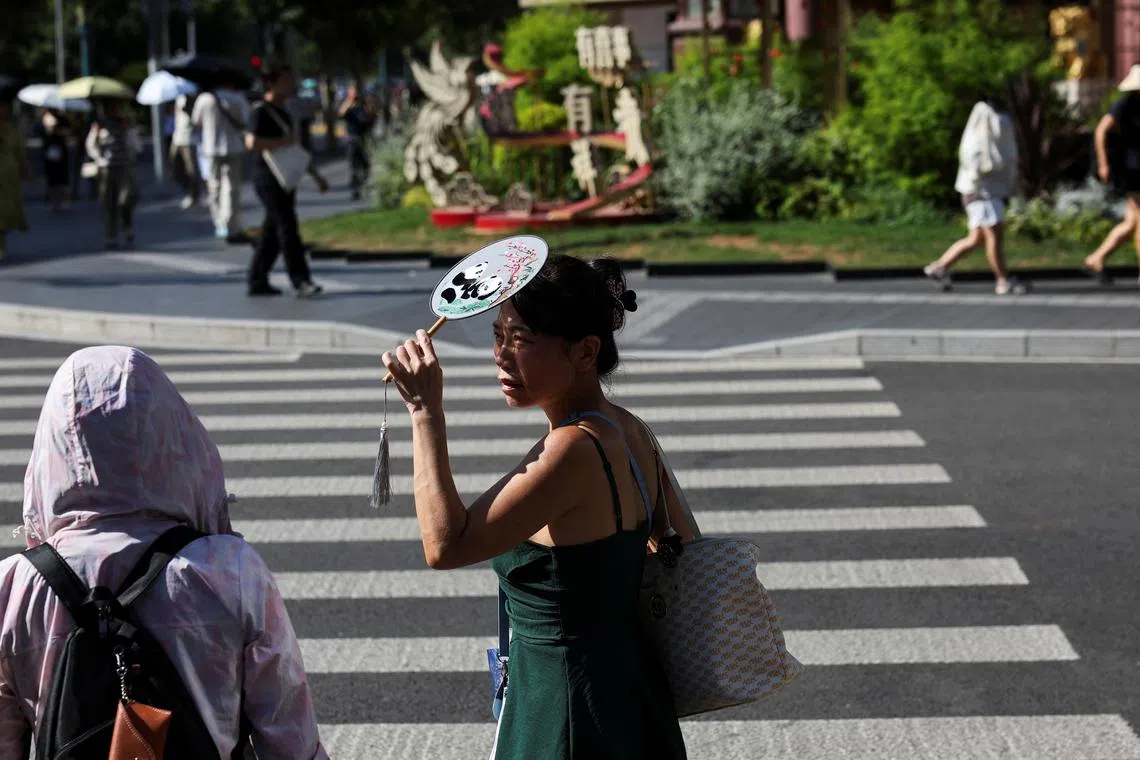 A person holds up a fan to cover her face from sunlight amid a yellow alert for heat, in Shanghai, China, on July 4. 