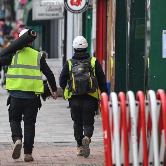 Construction workers walking down a street in London, Britain.