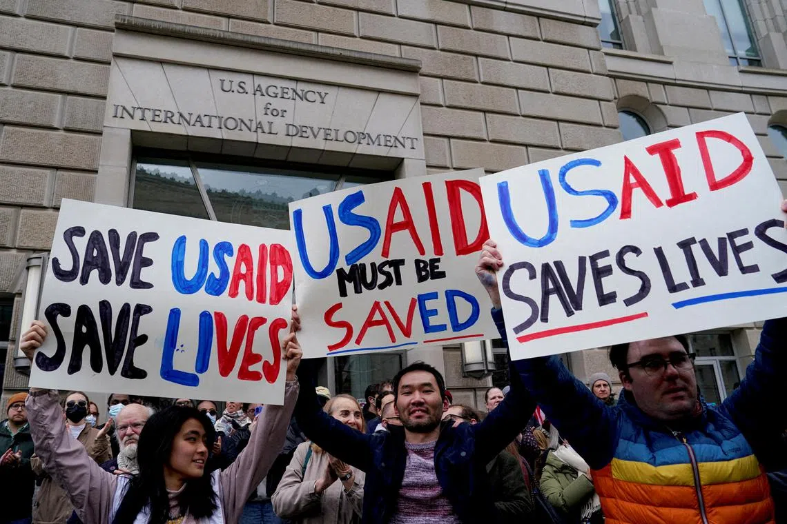 FILE PHOTO: People hold placards, as the USAID building sits closed to employees after a memo was issued advising agency personnel to work remotely, in Washington, D.C., U.S., February 3, 2025.