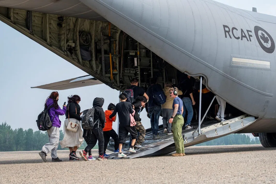Canadian Armed Forces Corporal Rhiann Nicol assists residents onto a CC-130J Hercules transport aircraft during their evacuation due to wildfires in Fort Hope, Ontario, Canada July 19, 2026. Master Corporal Natasha Punt/Canadian Armed Forces/Handout via REUTERS.