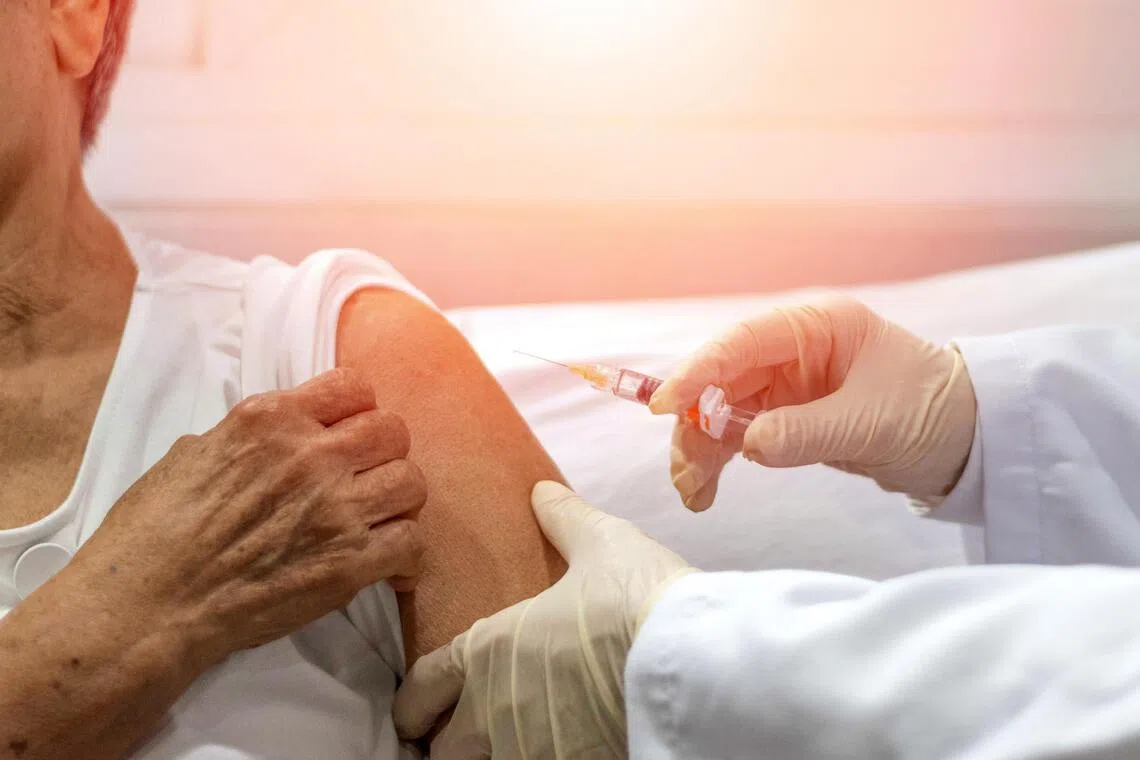 A healthcare worker gives an injection to a person's upper arm.