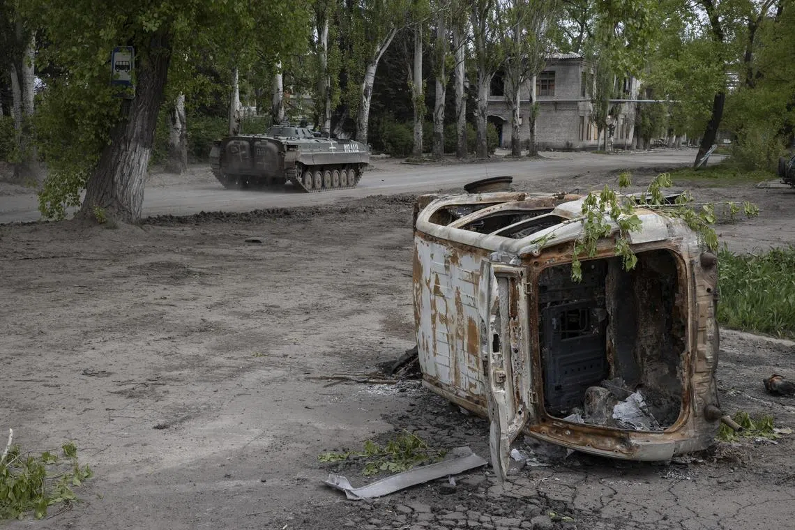 A Ukrainian infantry fighting vehicle passes a destroyed car in Chasiv Yar, a small town west of Bakhmut, Ukraine.