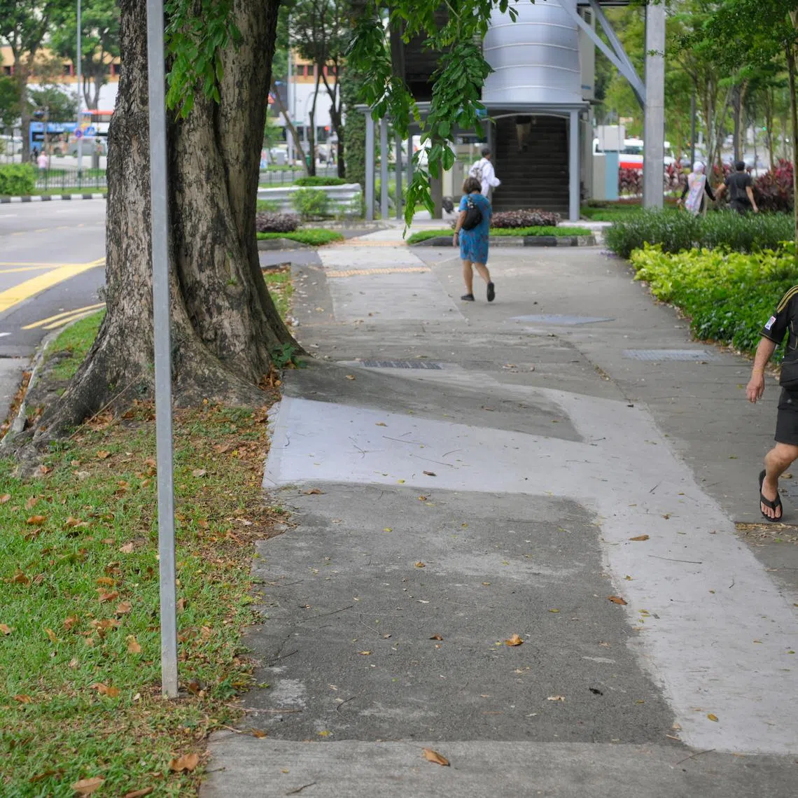 People walk along an uneven and damaged pavement along Jalan Bukit Merah on April 24, 2023.