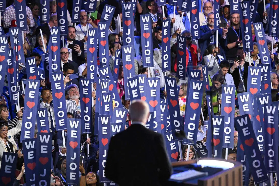 TOPSHOT - Delegates hold up signs as US President Joe Biden speaks on the first day of the Democratic National Convention (DNC) at the United Center in Chicago, Illinois, on August 19, 2024. Vice President Kamala Harris will formally accept the party’s nomination for president at the DNC which runs from August 19-22 in Chicago. (Photo by SAUL LOEB / AFP)