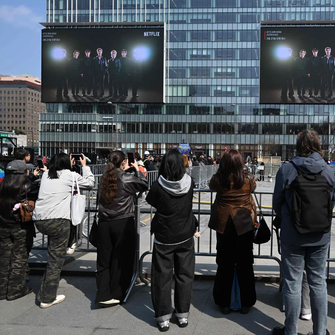 People look at electronic screens promoting the comeback concert of K-pop boy group BTS at Gwanghwamun Square in Seoul on March 20, 2026.