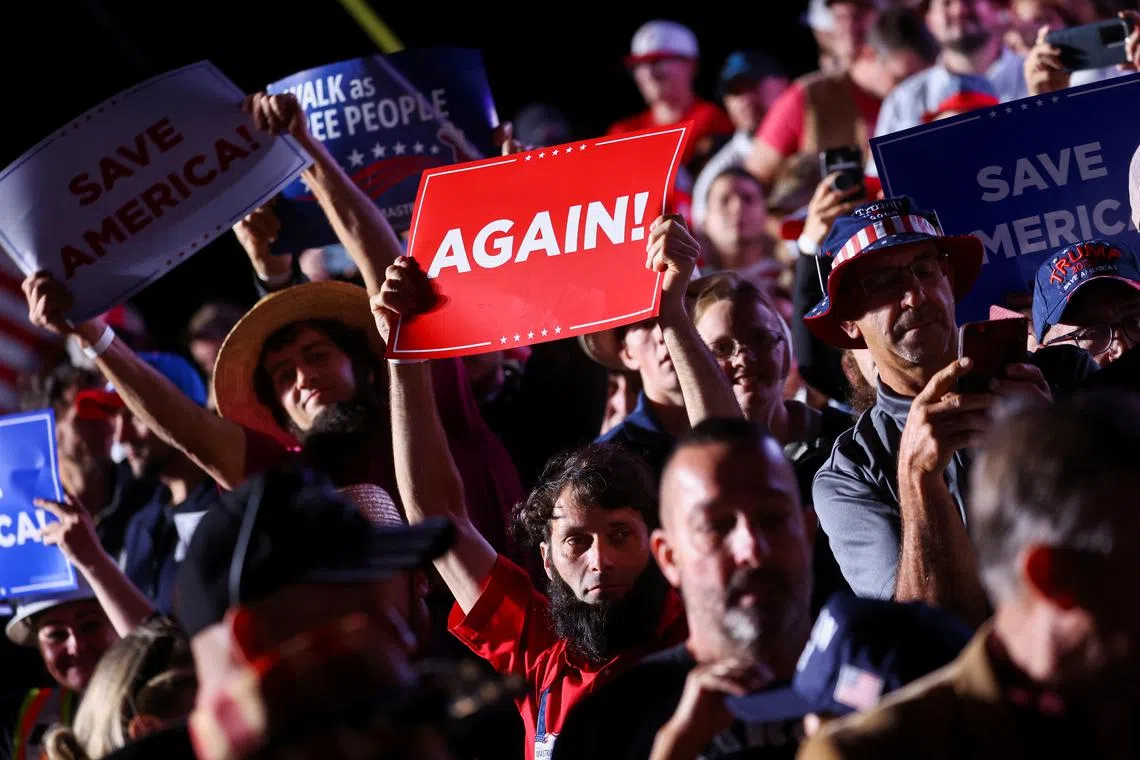 People hold up placards during a a pre-election rally held by former US President Donald Trump to support Republican candidates in Latrobe, Pennsylvania, on Nov 5, 2022.
