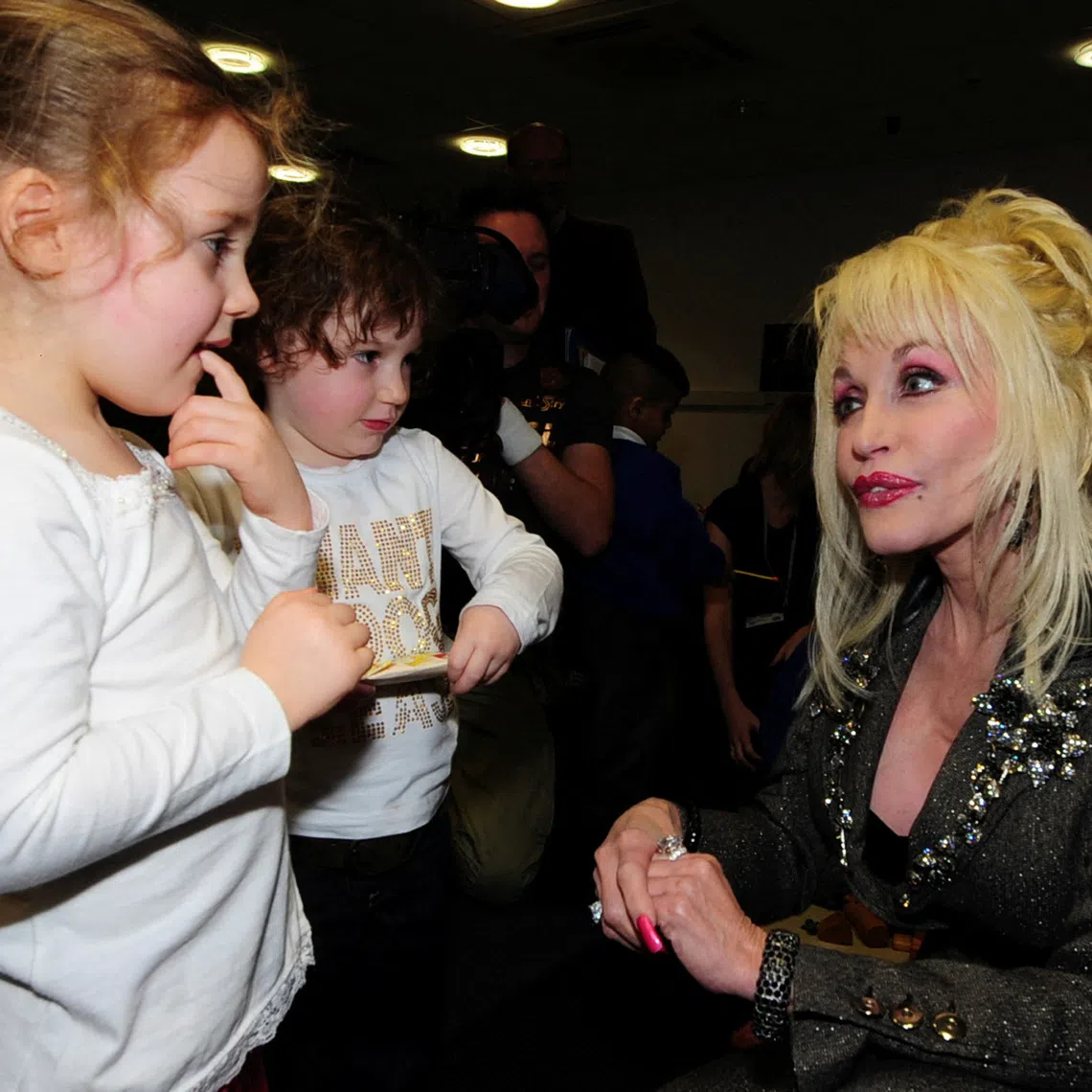 FILE PHOTO: U.S. singer Dolly Parton (R) speaks to children at the launch of her Imagination Library book project  at the Magna Centre in Sheffield in northern England December 5, 2007. Parton's Imagination Library project is an early literacy programme for children. REUTERS/Nigel Roddis/File Photo