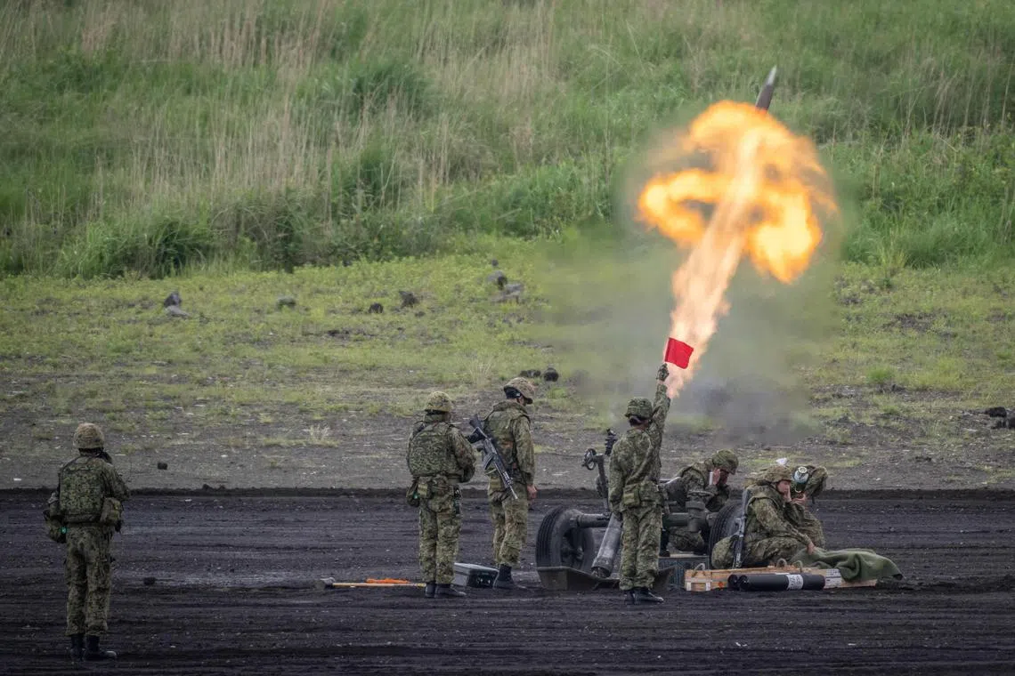 Members of the Japan Ground Self-Defense Force (JGSDF) operating a howitzer during a live fire exercise at East Fuji Maneuver Area in Gotemba on May 26, 2024. 