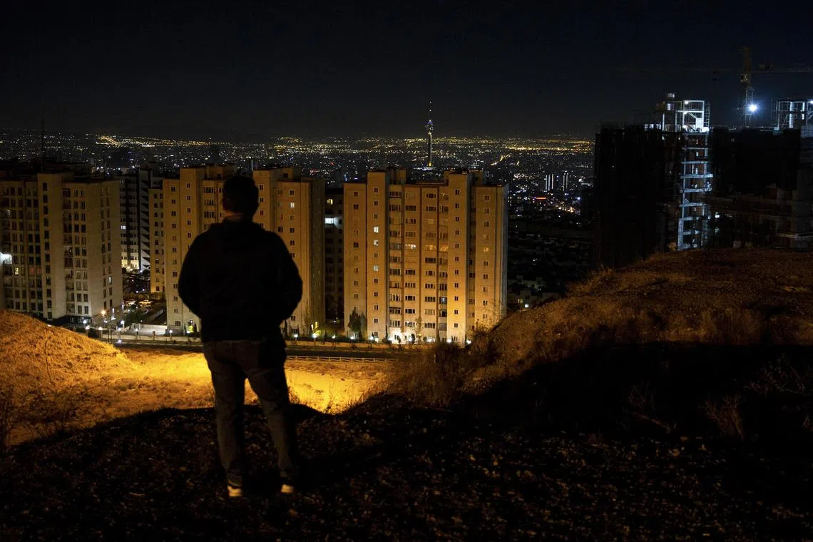 A man looks out over Tehran after hearing the sound of explosions on Oct 26 amid air strikes by Israel.
