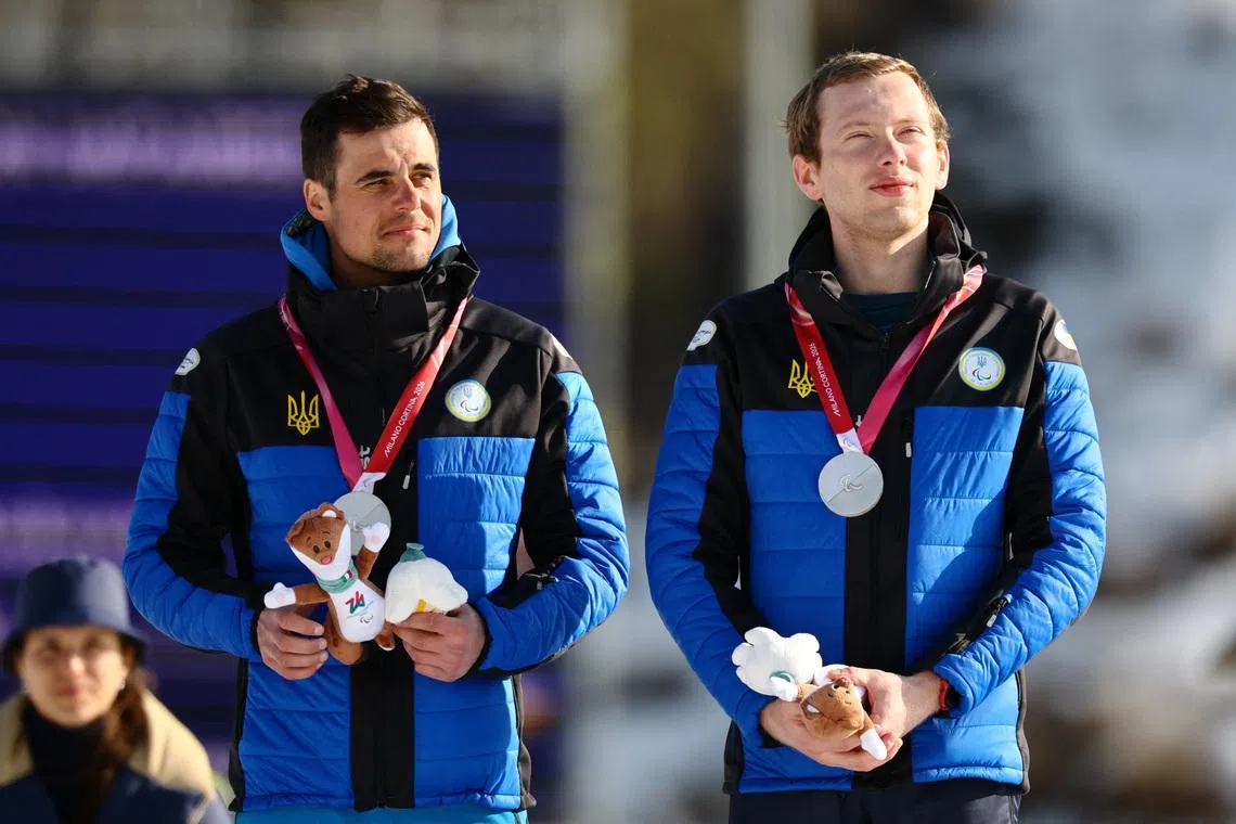 Milano Cortina 2026 Paralympics - Para Biathlon - Men's Individual Vision Impaired Victory Ceremony - Tesero Cross-Country Skiing Stadium, Lago, Italy - March 08, 2026. Silver medallist Maksym Murashkovskyi of Ukraine and guide Vitaliy Trush celebrate on the podium during the men's individual vision impaired victory ceremony REUTERS/Sarah Meyssonnier