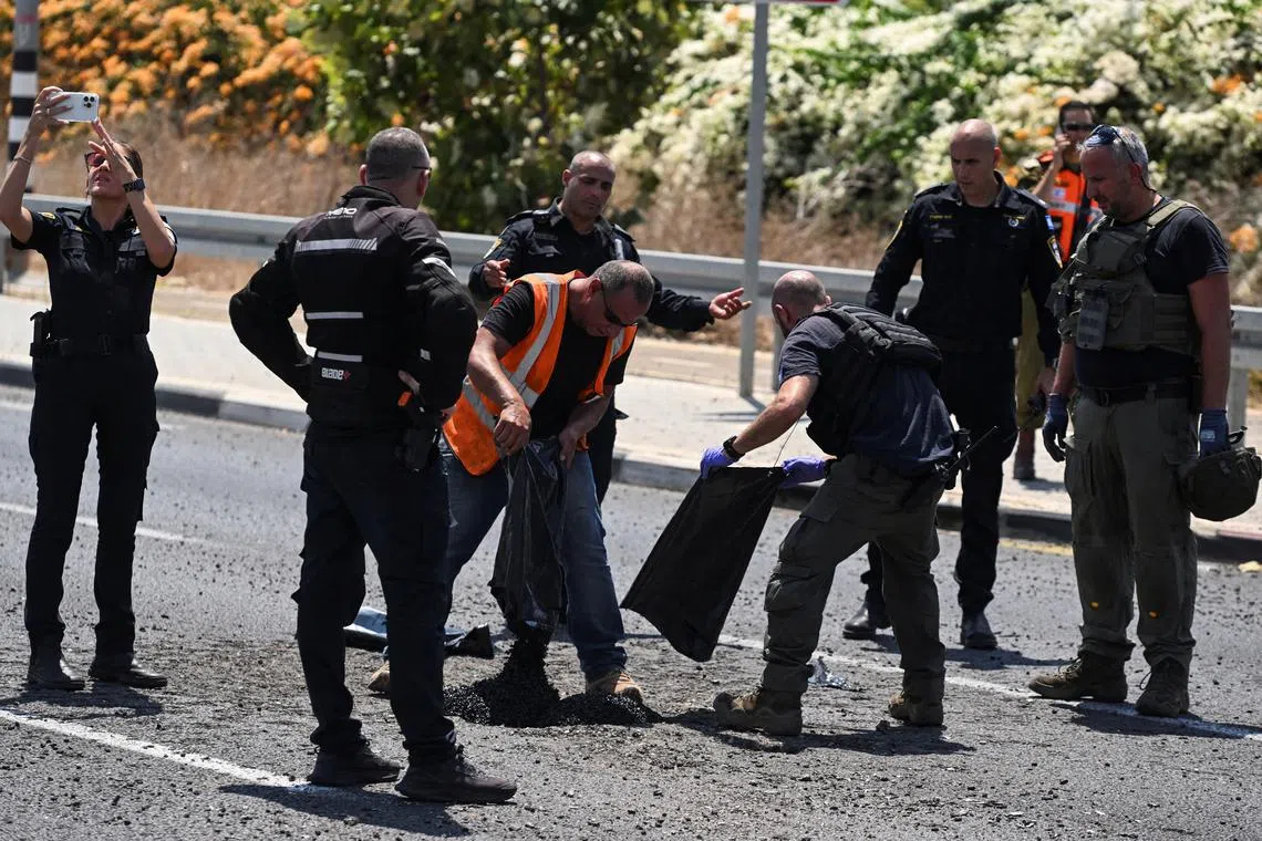 Israeli police and officials work at the impact site of a projectile, after Lebanon's armed group Hezbollah said it launched a swarm of attack drones against military targets in northern Israel, in Nahariya, Israel, August 6, 2024. REUTERS/Rami Shlush