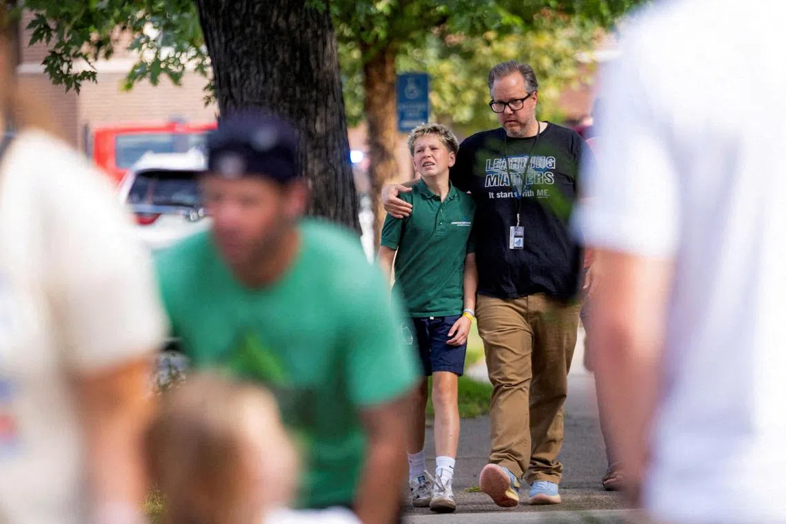 Families and loved ones walk outside the police barricades after a shooting at Annunciation Church, which is also home to an elementary school, in Minneapolis.