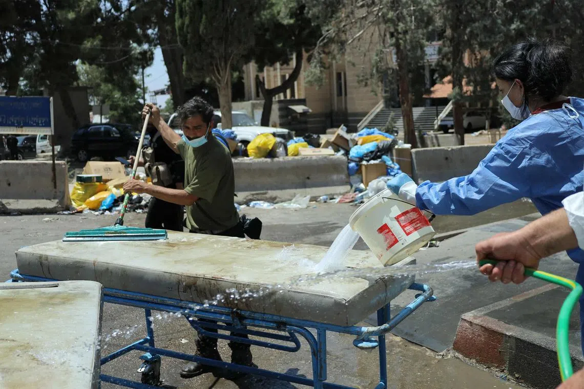 Medical workers clean and disinfect a hospital bed outside Sweida National Hospital in southern Syria's predominantly Druze city of Sweida on July 20, 2025.