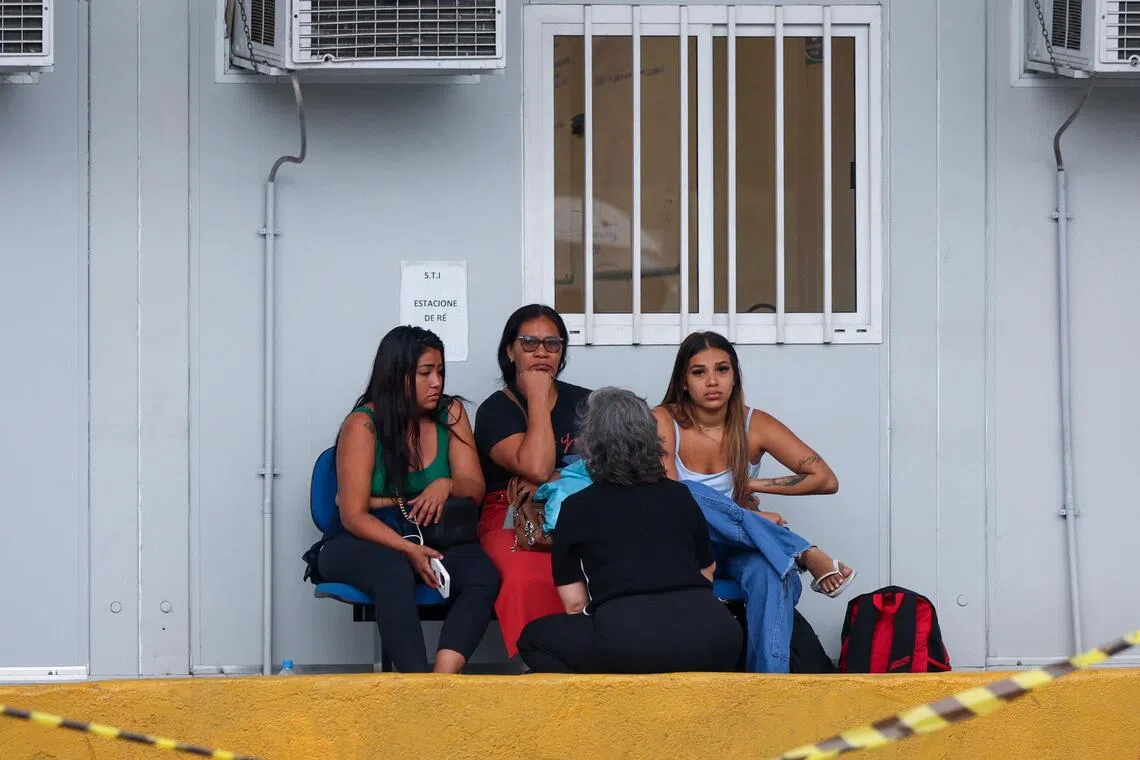 People sitting outside a Rio de Janeiro morgue on Oct 30, following Oct 28 police raids in which 121 people died. 