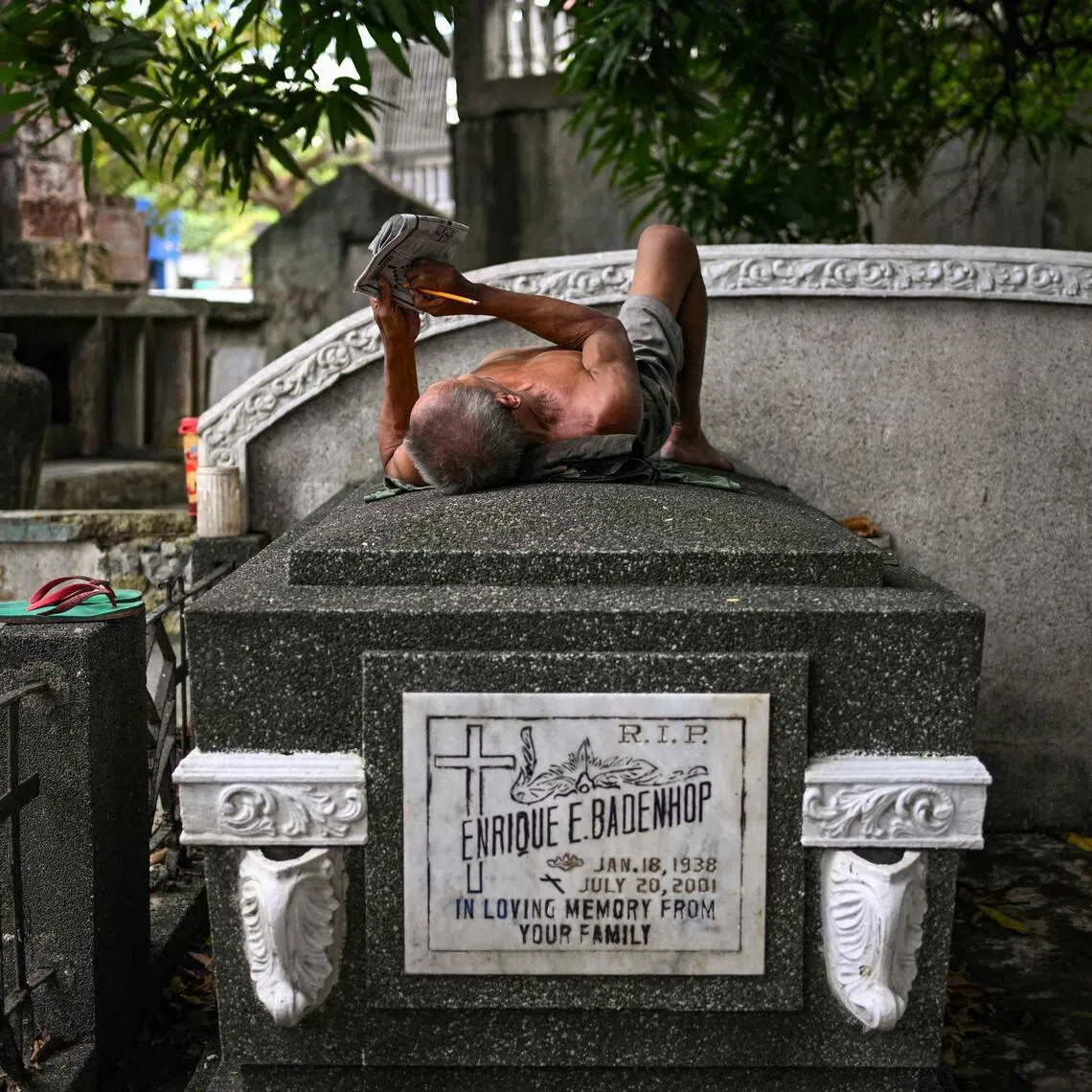 A man lies on top of a tomb at the 54ha Manila North Cemetery that is home to about 6,000 informal settlers and at least a million dead.

