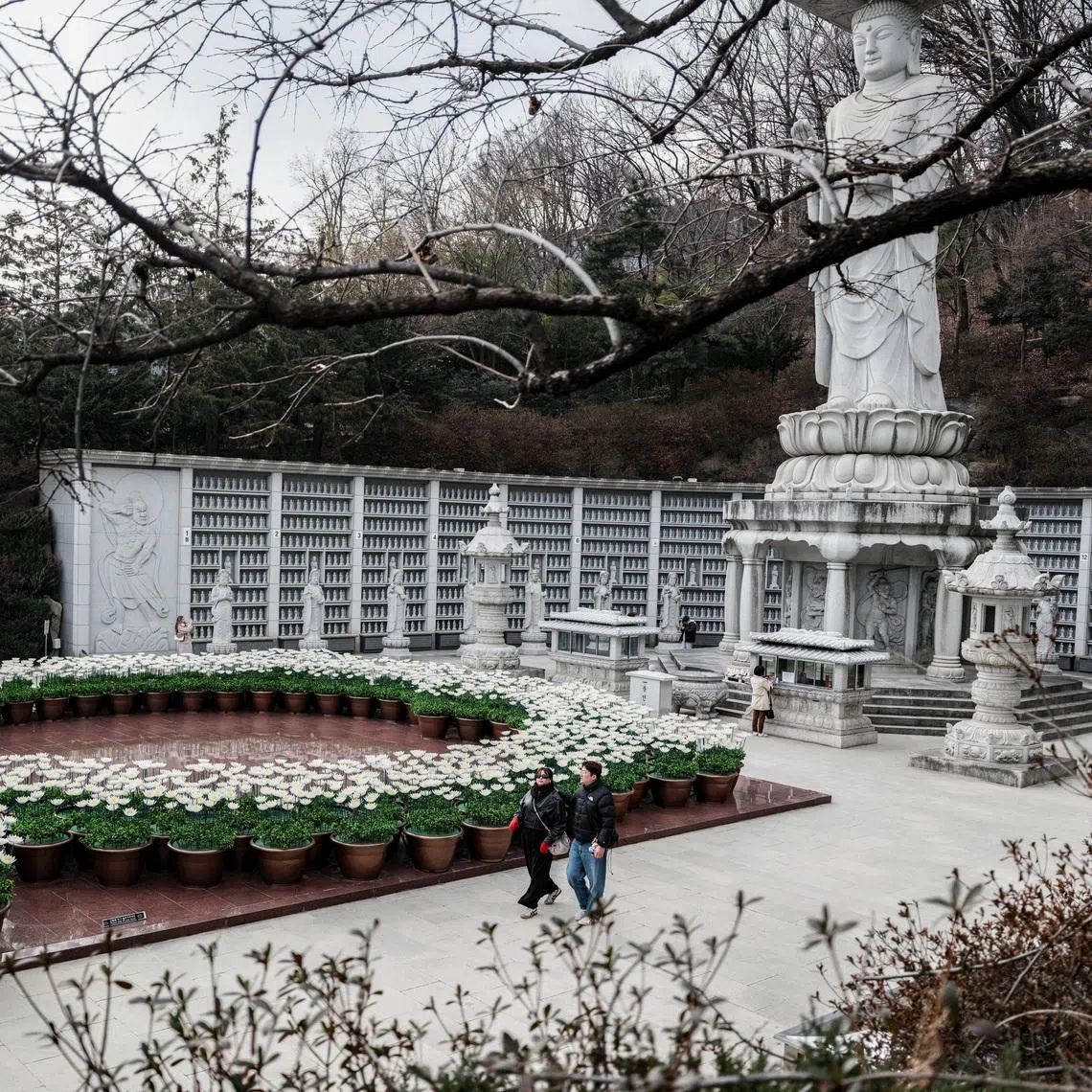 People walk past Buddhist statue of Bongeunsa Temple in Seoul, South Korea, March 9.