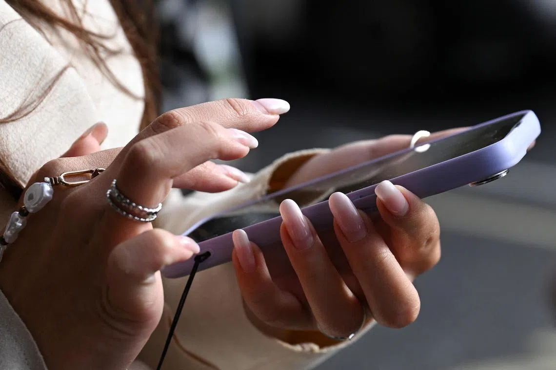 A woman holds her phone on the street in Westminster, in London, Britain, October 11, 2024. REUTERS/Jaimi Joy