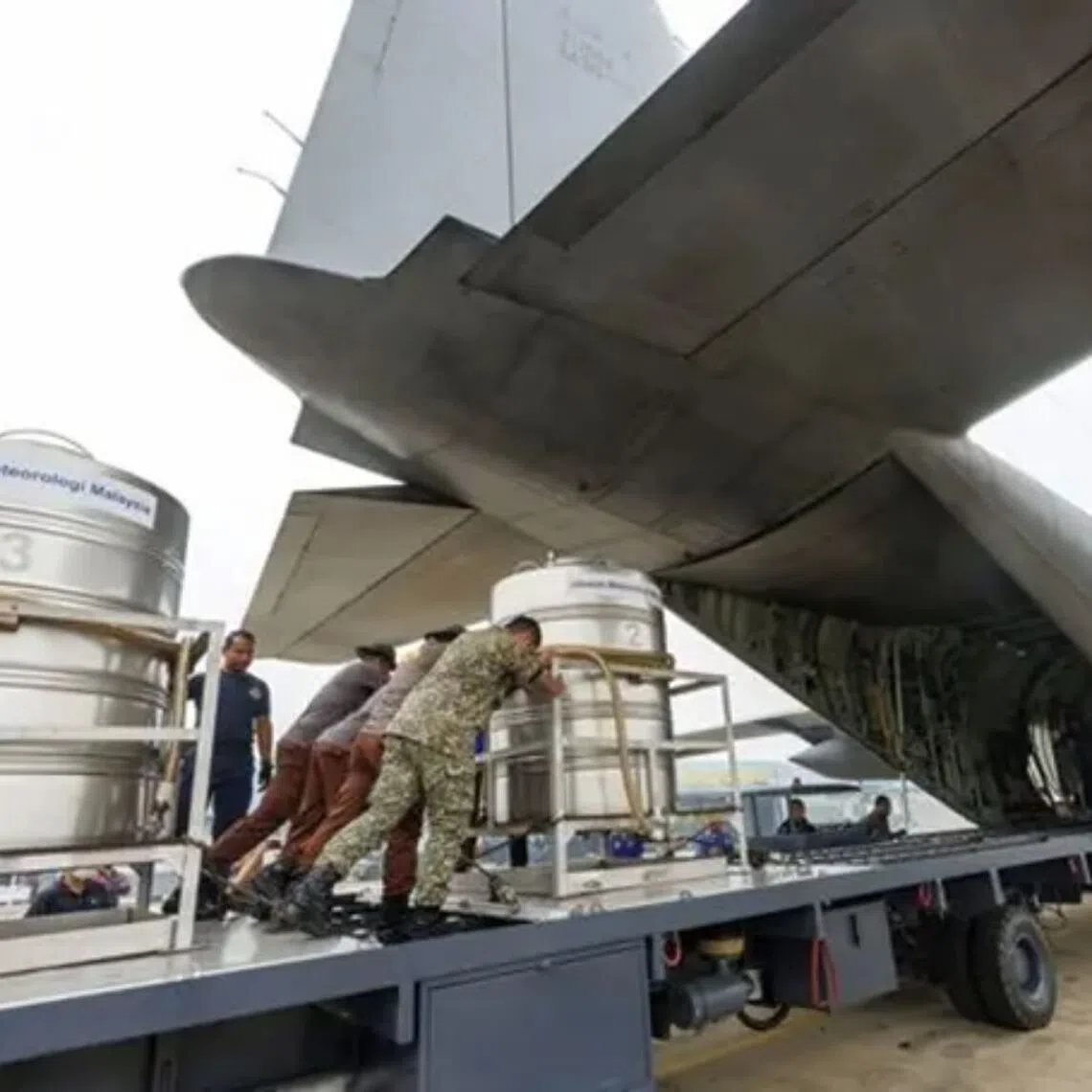 Malaysia’s air force personnel assist in loading cloud-seeding tanks into an aircraft for cloud seeding operations.