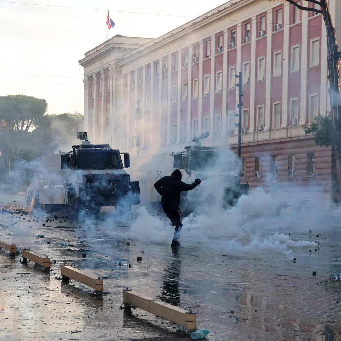 A demonstrator reacts to tear gas near police forces guarding next to the parliament building amid an anti-government protest by students in Tirana, Albania, October 16, 2026. REUTERS/Louisa Gouliamaki