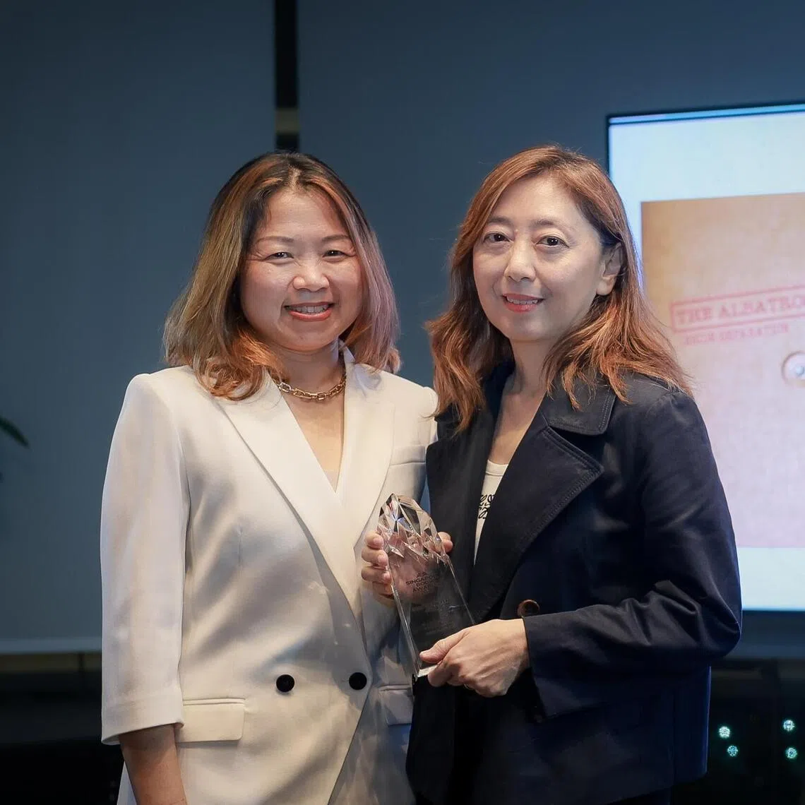 The Straits Times chief columnist and senior editor of publications Sumiko Tan receives the Book Of The Year award from NLB CEO Melissa Tam (left, white top) at the Singapore Book Awards.