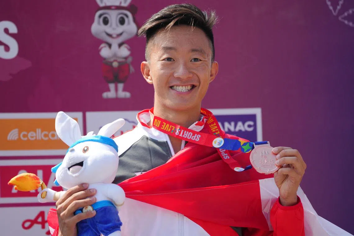Singapore's  Bryce Chong celebrating on the podium after winning bronze in the men's aquathlon.
