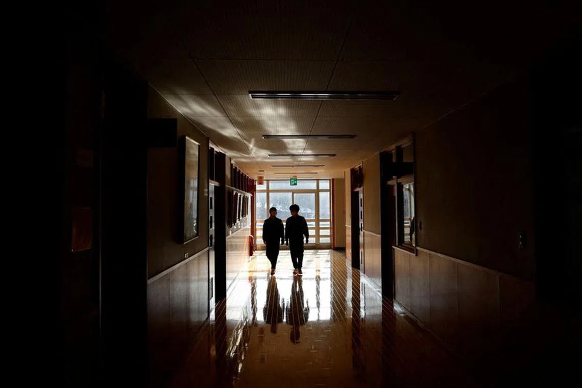 FILE PHOTO: Eita Sato, 15, and Aoi Hoshi, 15, walk along the corridors of Yumoto Junior High School, where they are the only two students, a few days before their graduation and the institution's closing ceremony, in Ten-ei Village, Fukushima Prefecture, Japan, March 9, 2023.  REUTERS/Issei Kato/File Photo