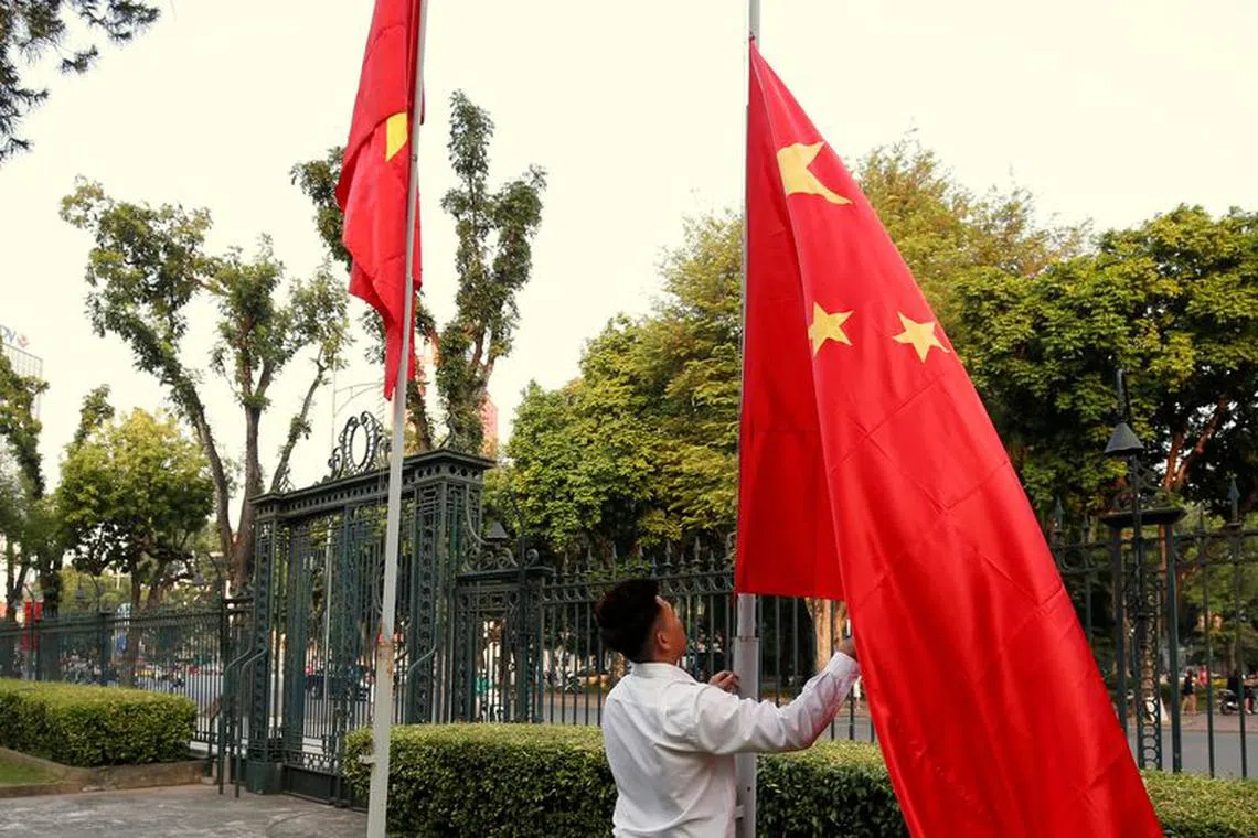 A man raises a Chinese flag (R) next to a Vietnamese flag before a meeting between China's Foreign Minister Wang Yi and Vietnam's Deputy Prime Minister and Foreign Minister Pham Binh Minh at the Government Office in Hanoi, Vietnam November 2, 2017. REUTERS/Kham/File Photo