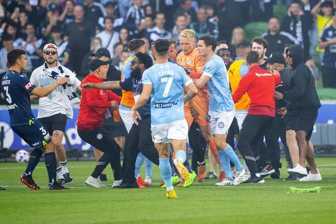 A bleeding Melbourne City goalkeeper Tom Glover (in orange) is escorted from the pitch after Melbourne Victory fans attacked him in a violent pitch during their A-League match at AAMI Park on ?Dec 17. The referee also suffered a head cut and the game was abandoned.