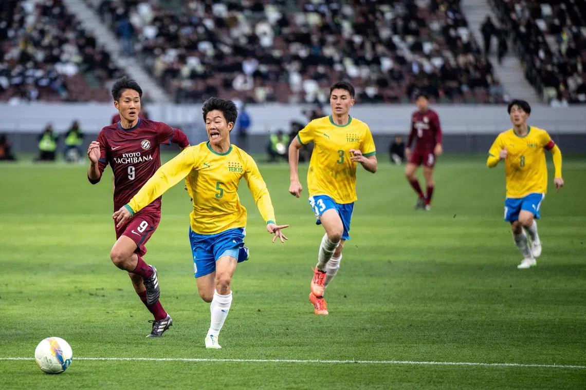 Players competing during the high-school football match between Tokyo's Teikyo (yellow) and Kyoto's Kyoto Tachibana in the 103rd tournament at the National Stadium in Tokyo. 