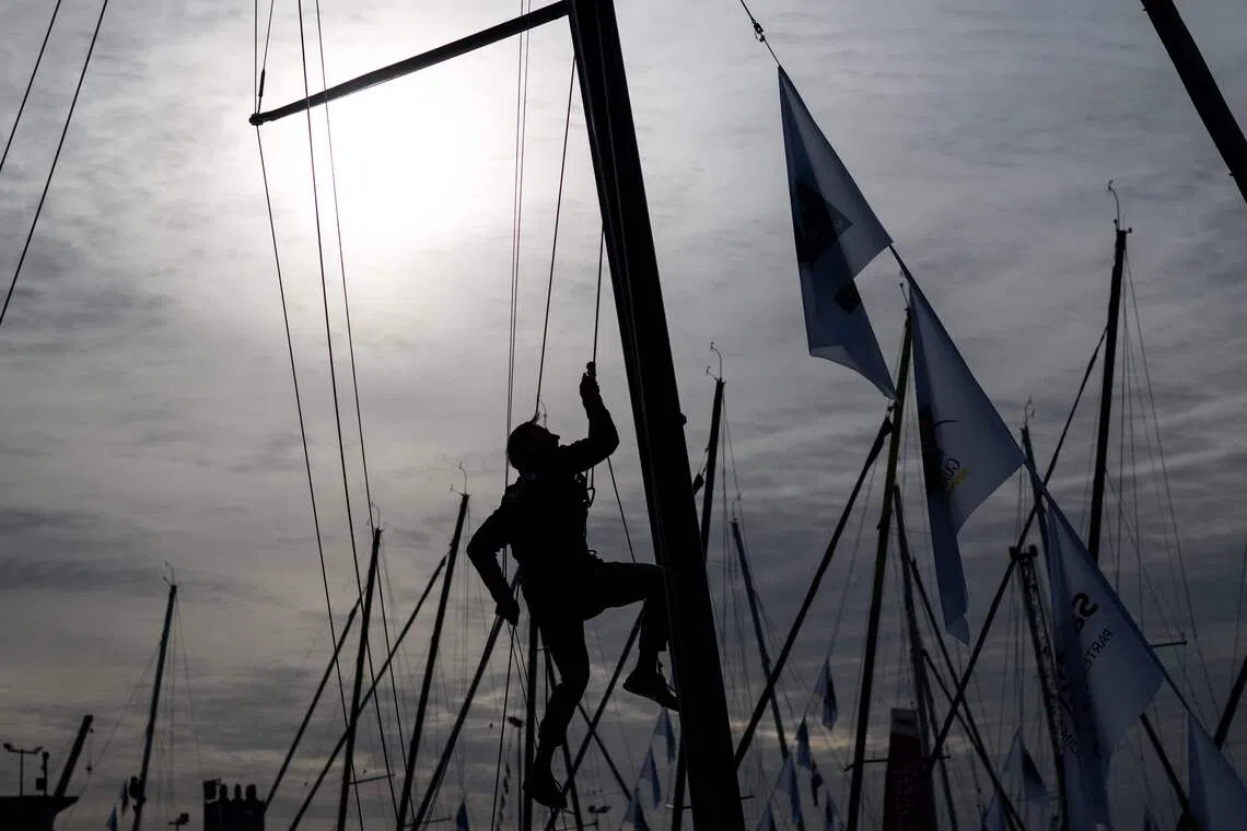 TOPSHOT - A sailor climbs the mast of a class 40 monhull ahead of the start of the 13th Route du Rhum Destination Guadeloupe on October 29, 2026. (Photo by Sebastien Salom-Gomis / AFP)