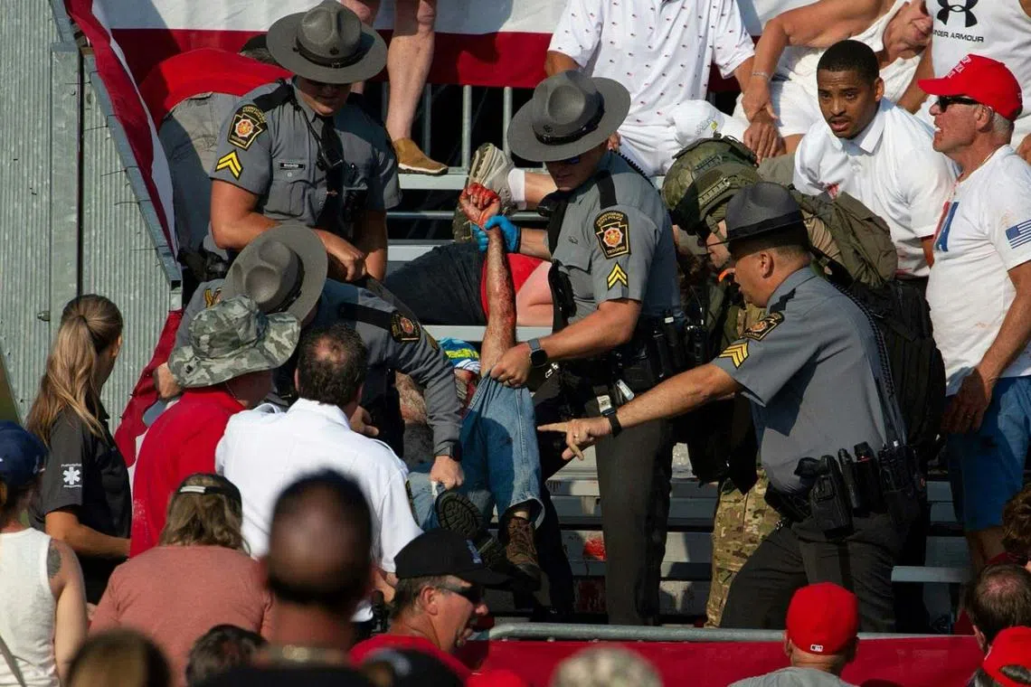 A person is removed by state police from the stands after guns were fired at Republican candidate Donald Trump at a campaign event. 