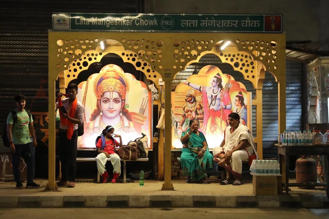 People sitting at a bus stop decorated with photographs of Lord Rama, on the eve of General elections in Ayodhya, Uttar Pradesh, India on 19 May 2024. Voting for the fifth phase of the Indian general elections will be held on 20 May 2024. 