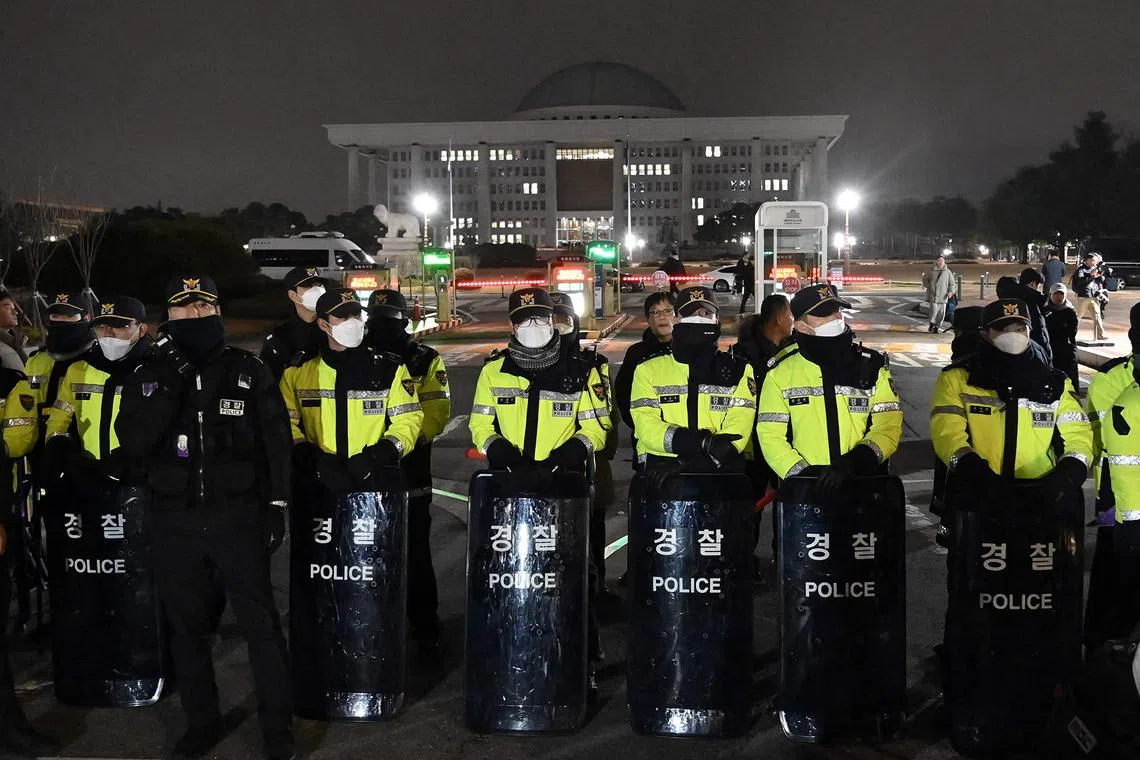 Police standing guard in front of the main gate of the National Assembly in Seoul on Dec 3, 2024, after South Korea's President Yoon Suk Yeol declared emergency martial law. 