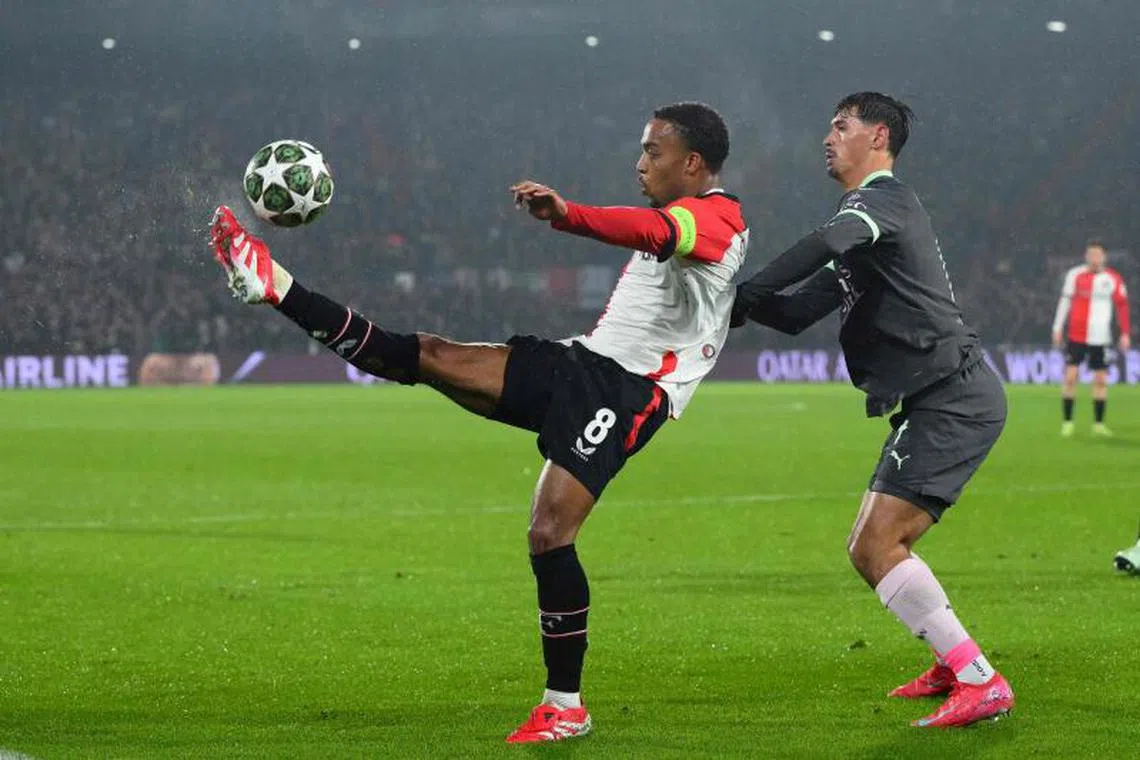 Feyenoord's Dutch midfielder #08 Quinten Timber (L) fights for the ball with AC Milan's Dutch midfielder #14 Tijani Reijnders during the UEFA Champions League knockout phase play-off 1st leg football match between Feyenoord Rotterdam and AC Milan at the Stadion Feijenoord "De Kuip" in Rotterdam, on February 12, 2025. (Photo by JOHN THYS / AFP)