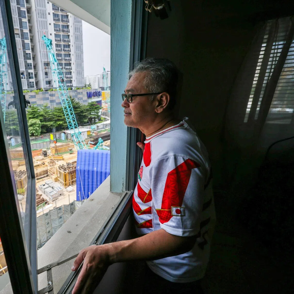 Mr Abdul Rashid, whose flat faces the Cross Island Line Punggol extension construction site, looks out at the construction work below his flat on Aug 13.