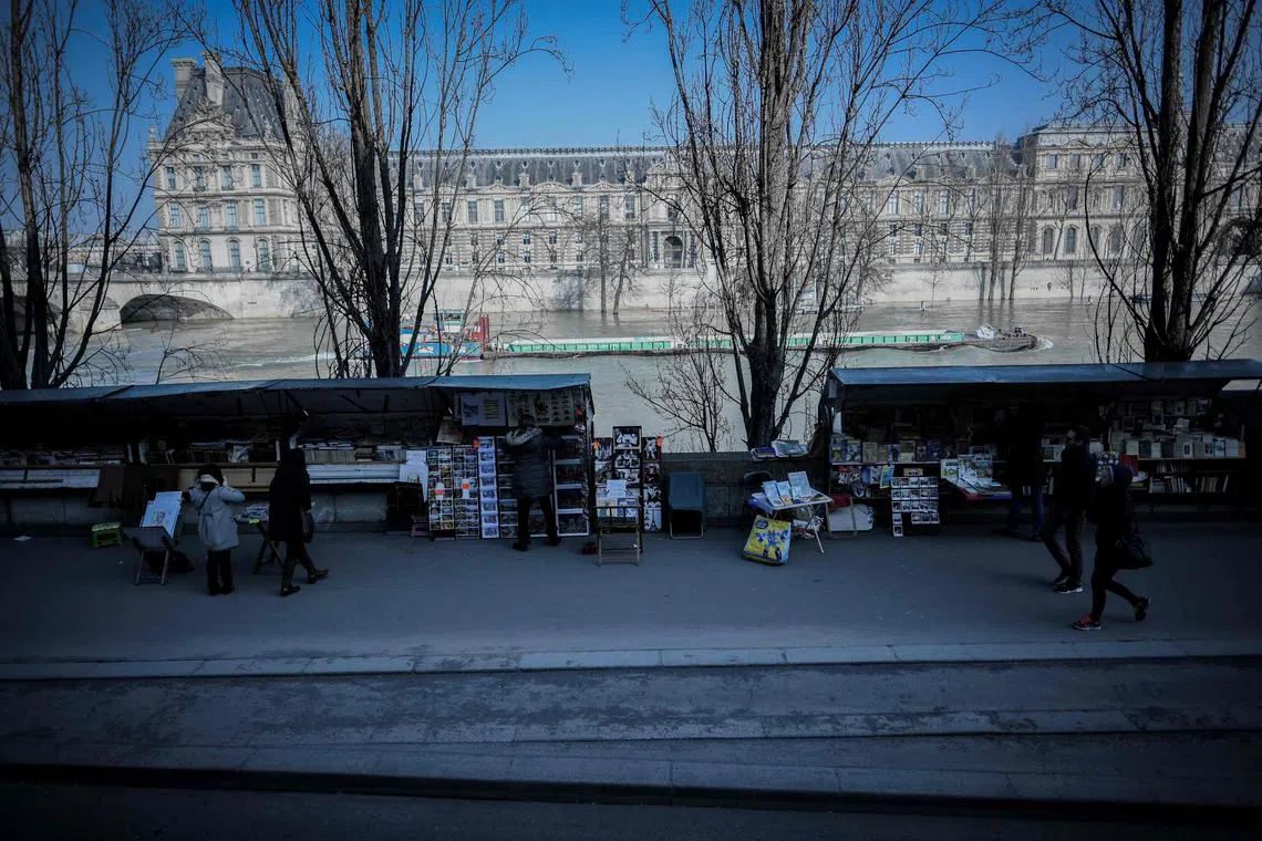 (FILES) A picture taken from a double-deck tourist bus on February 22, 2018 shows the stalls of the Bouquinistes of Paris, booksellers of used and antiquarian books along the banks of the river Seine, in Paris. Parisian booksellers, the world's largest open-air bookshop, who have been operating on the banks of the Seine for 450 years, are refusing to be moved by the authorities to provide security for the opening ceremony of the Olympic Games, sources told us on July 27, 2023. (Photo by STEPHANE DE SAKUTIN / AFP)