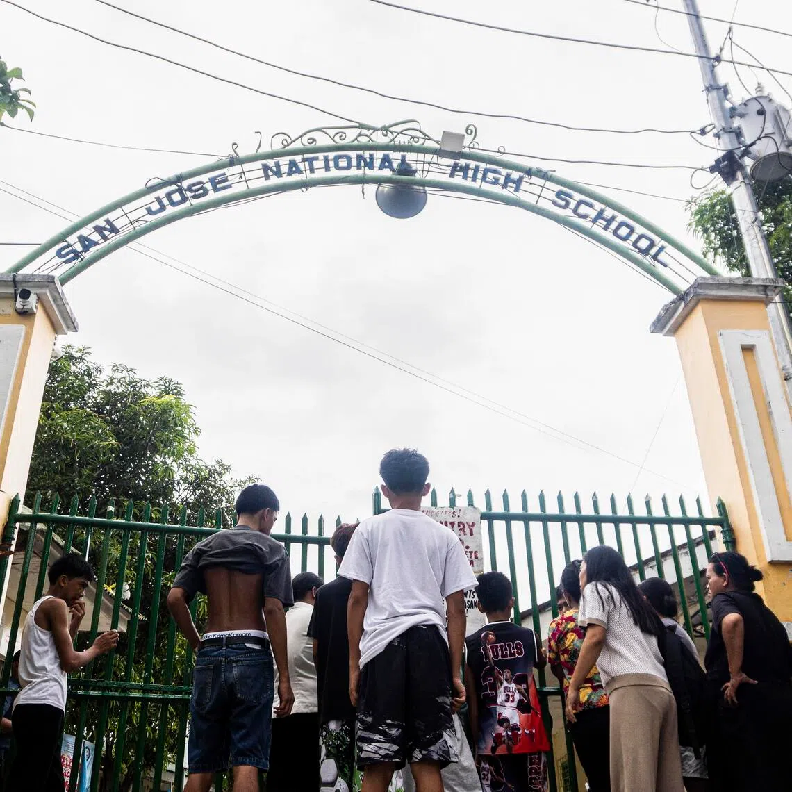People at the gates of San Jose National High School in Tacloban City in Leyte province, central Philippines, after two students opened fire on their classmates on June 22.