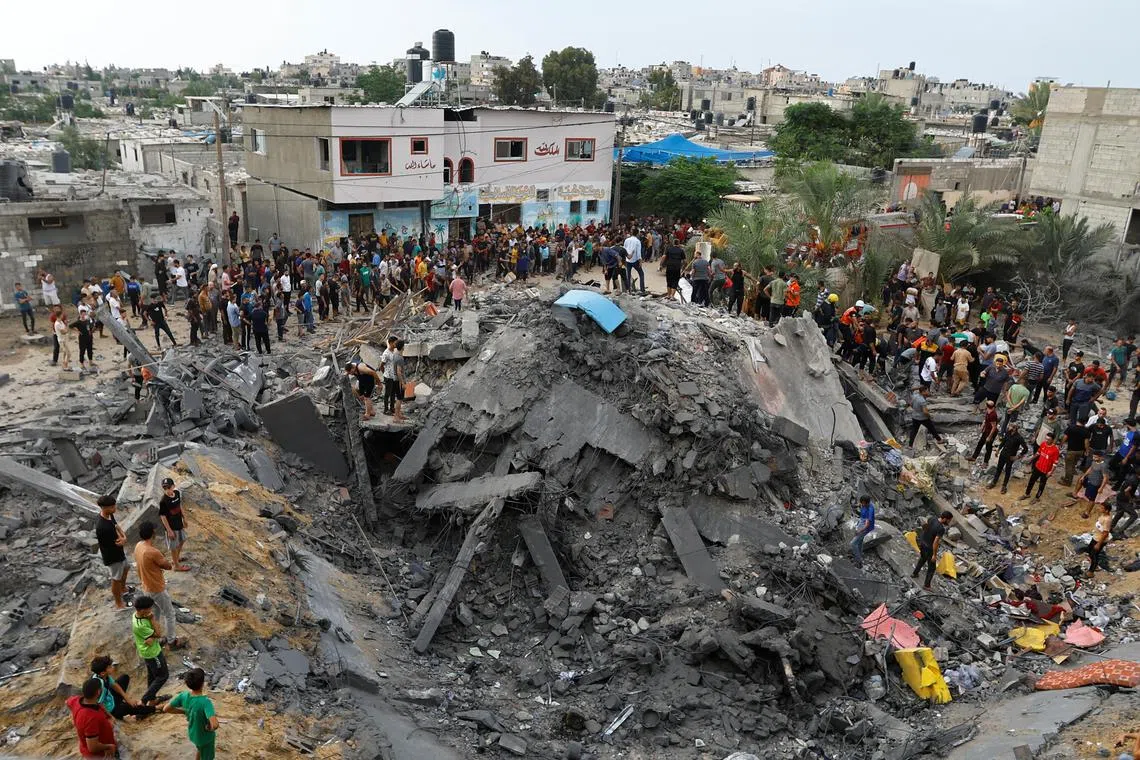 Palestinians gathering around the rubble of a building destroyed by Israeli strikes in the southern Gaza Strip on Oct 9.